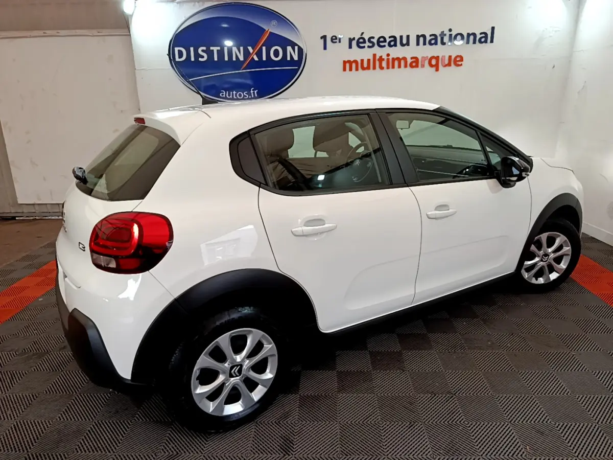 Vue 3/4 arrière droite d'une Citroën C3 blanche 2018 avec jantes alliage et protections noires sur passages de roues.
