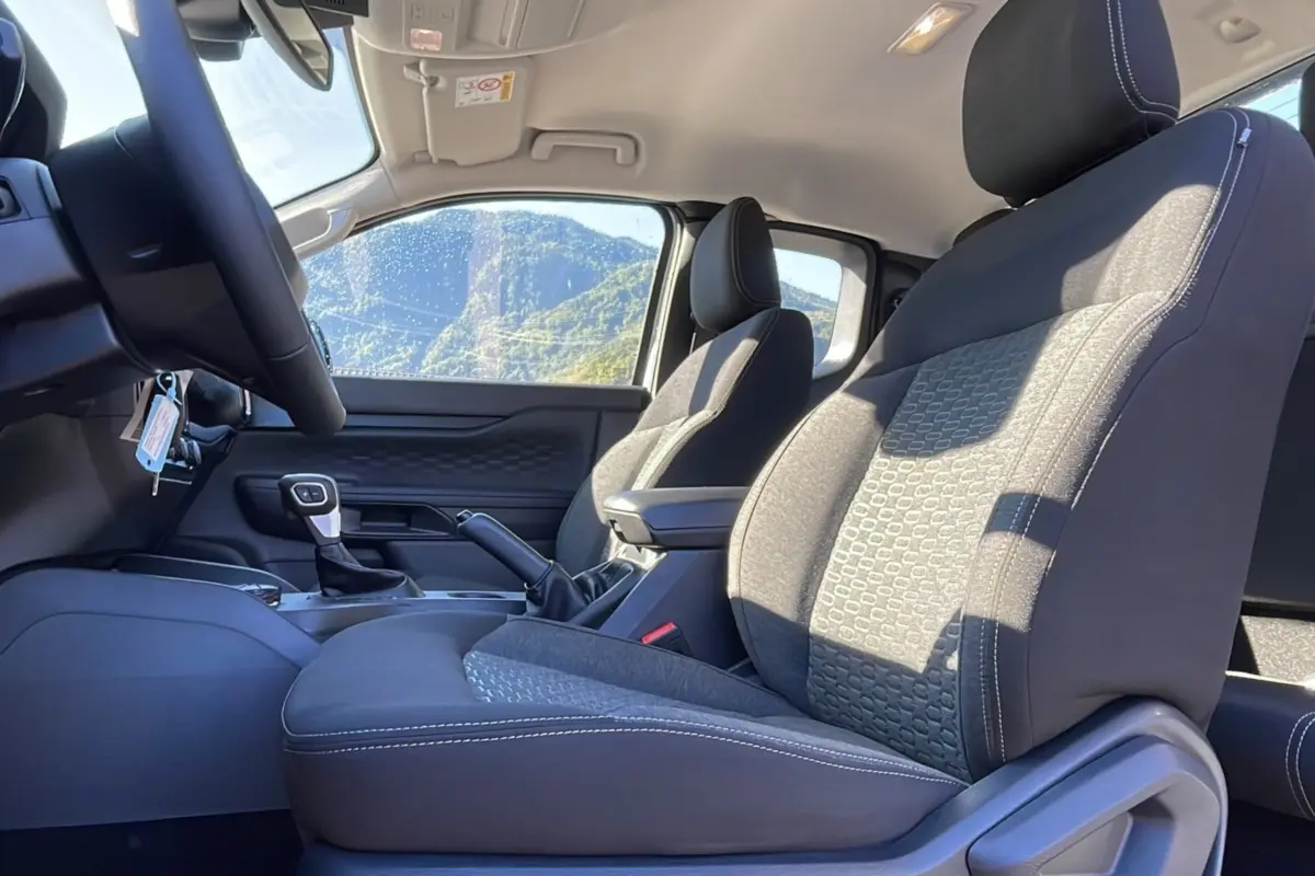 Intérieur du Ford Ranger 2025 en vue latérale côté conducteur, sièges tissu gris avec motifs et console centrale visible.