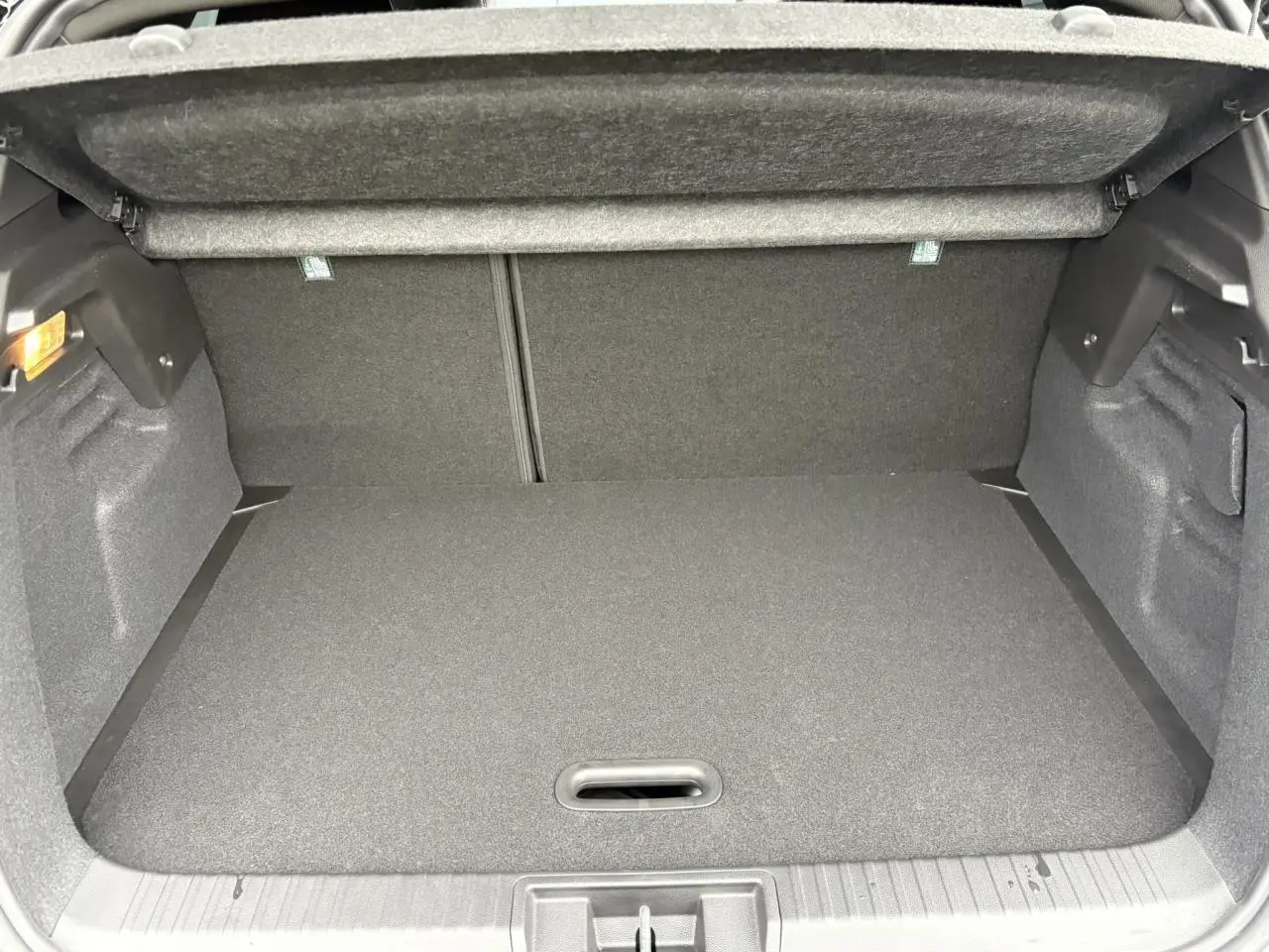 Coffre ouvert vu de face d’un Renault Captur blanc nacré avec intérieur de coffre gris foncé.