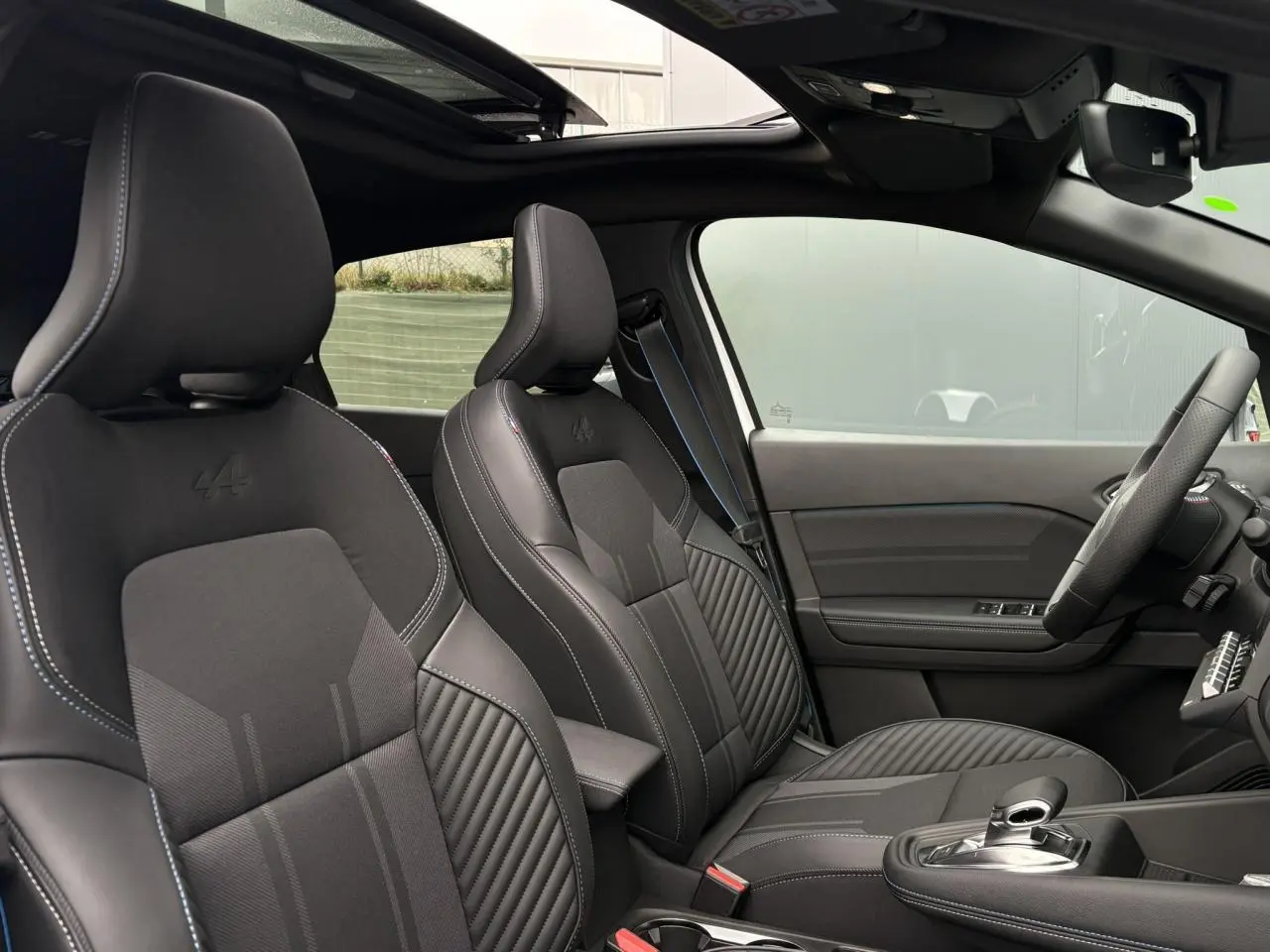 Vue intérieure côté droit du Renault Captur Esprit Alpine 2025, sièges noirs avec logo Alpine et toit ouvrant visible