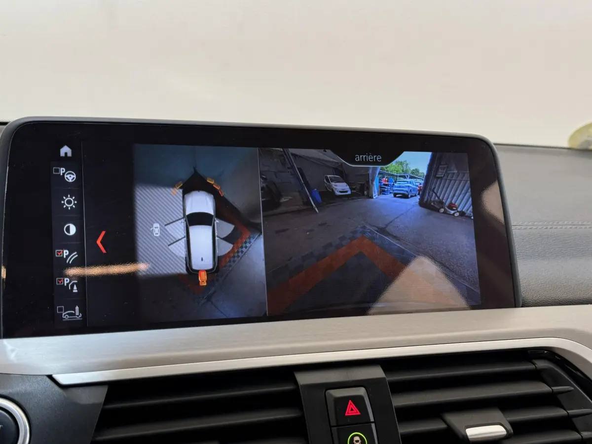 Écran tactile du système de navigation affichant la caméra de recul et vue 360° dans un BMW X3 gris foncé.