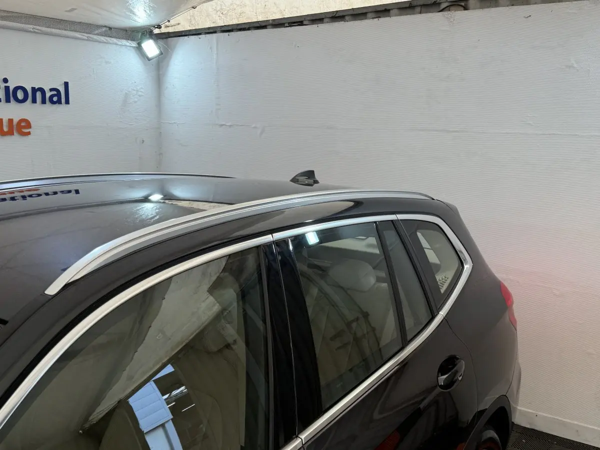 Vue de profil arrière droit d’un BMW X3 xDrive30d gris foncé avec barres de toit chromées et antenne requin.