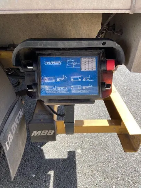 Gros plan sur la commande bleue du hayon Palfinger sous le châssis jaune du Ford Transit Chassis Cabine T350 2015.