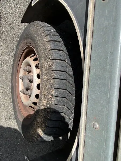 Gros plan sur la roue avant gauche usée du Ford Transit Chassis Cabine jaune, montrant la jante métallique rouillée.