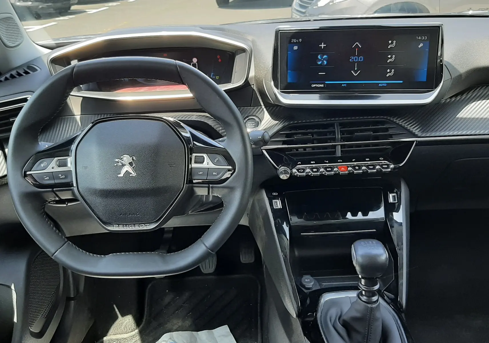 Vue intérieure du tableau de bord et volant du Peugeot 2008 gris Artense, avec écran tactile et boîte manuelle visible.