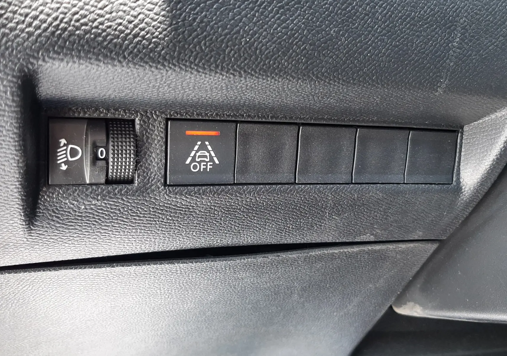 Gros plan sur les commandes noires du tableau de bord du Peugeot 2008 gris Artense, avec bouton d'alerte de franchissement de ligne désactivé.