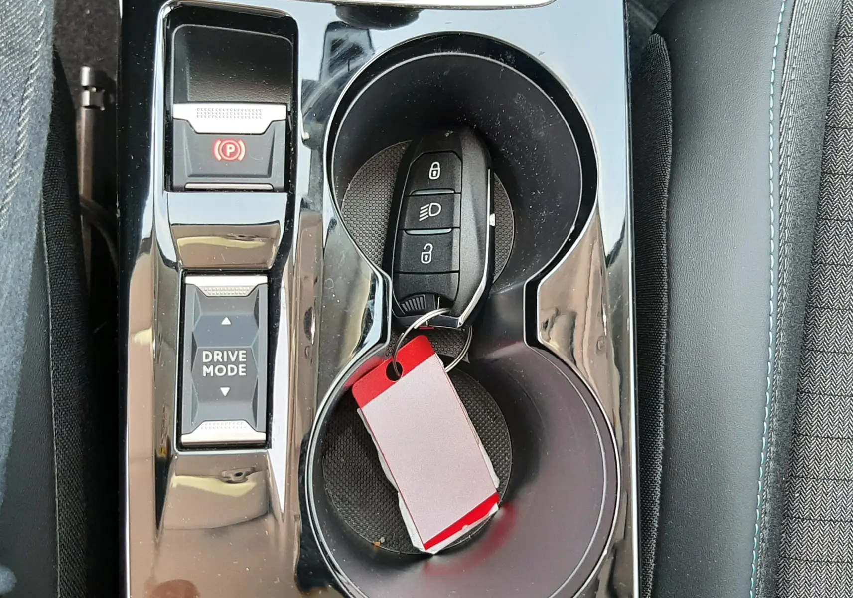 Vue rapprochée de la console centrale noire brillante du Peugeot 2008 avec clé et porte-clés dans les porte-gobelets.