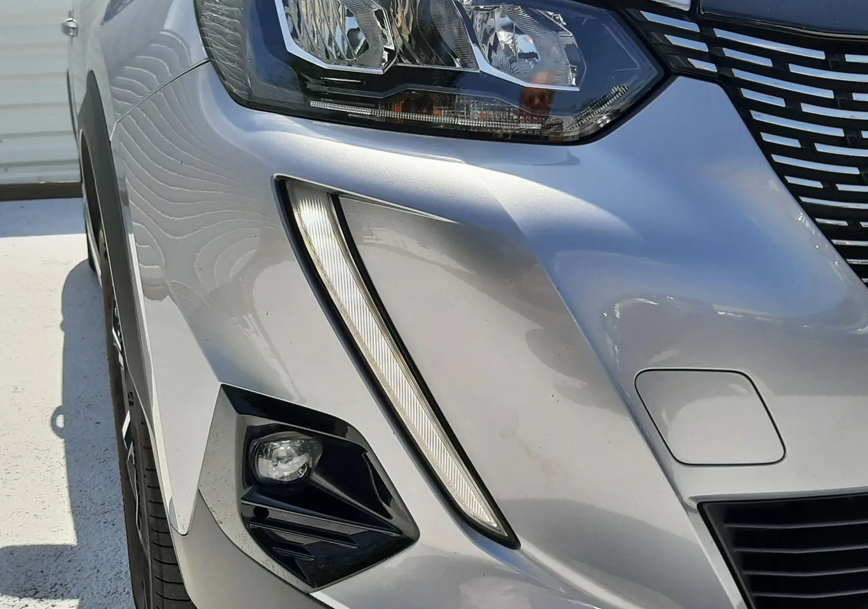 Gros plan sur l'avant droit gris Artense du Peugeot 2008 2022, mettant en valeur son phare LED et la calandre distinctive.