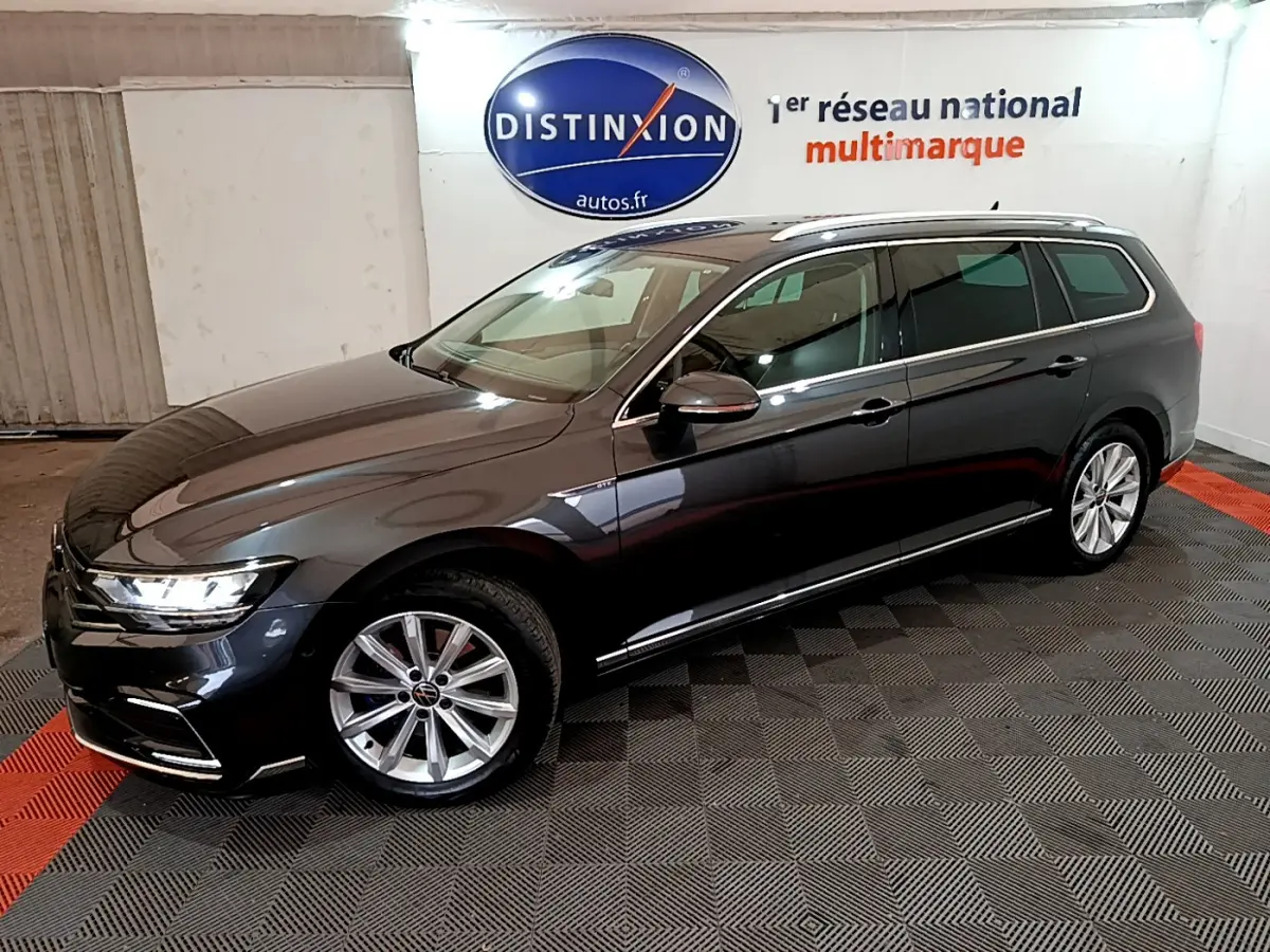 Volkswagen Passat SW hybride rechargeable gris foncé vue 3/4 avant droit, jantes alliage et feux LED allumés.
