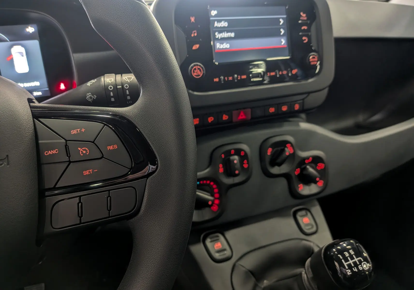 Intérieur de la Fiat Panda 2025 bleu Italia, vue rapprochée sur le volant, la console centrale et le levier de vitesses manuel.