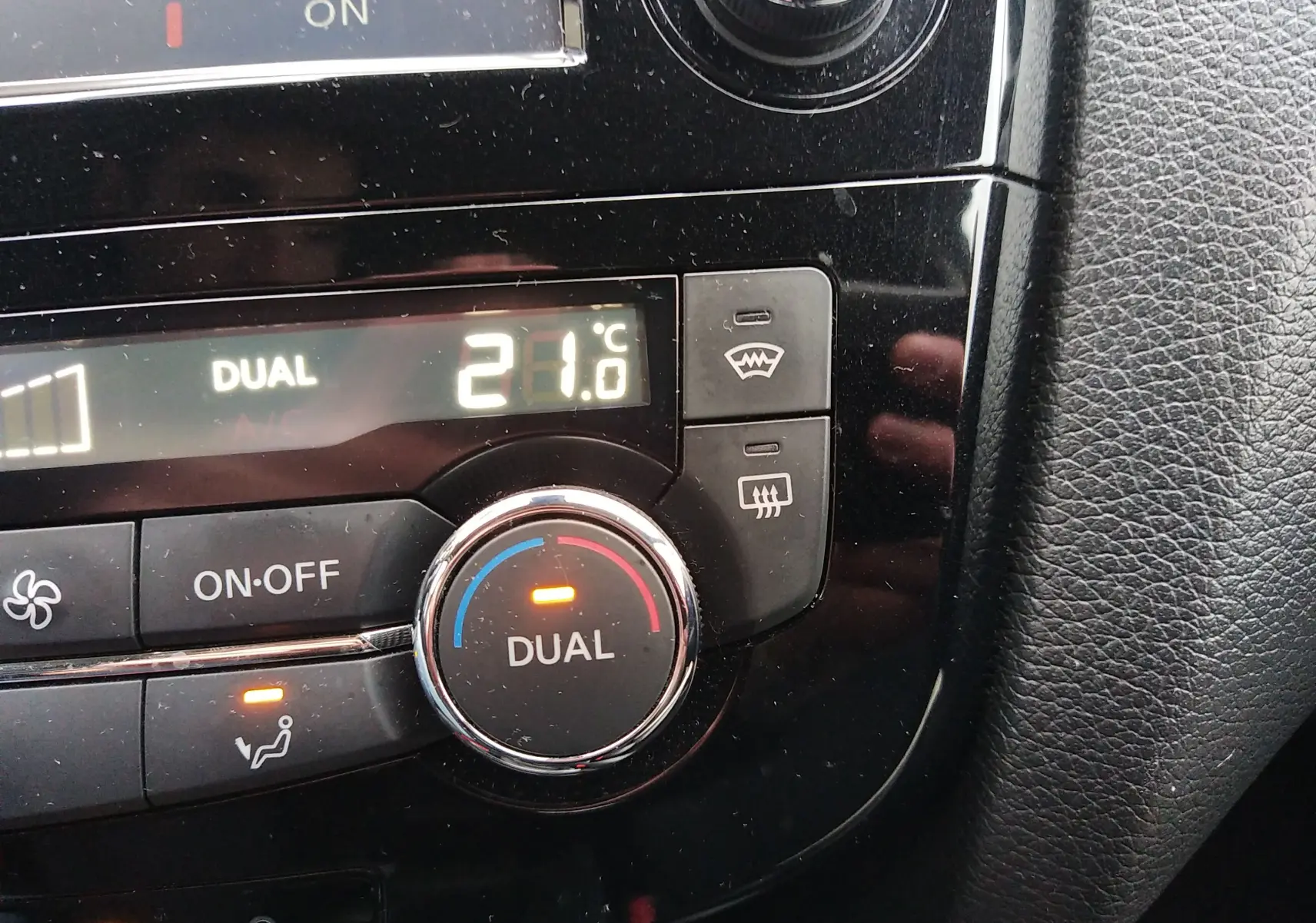 Gros plan sur la molette de climatisation dual noir brillant du Nissan Qashqai 2019 affichant 21°C.