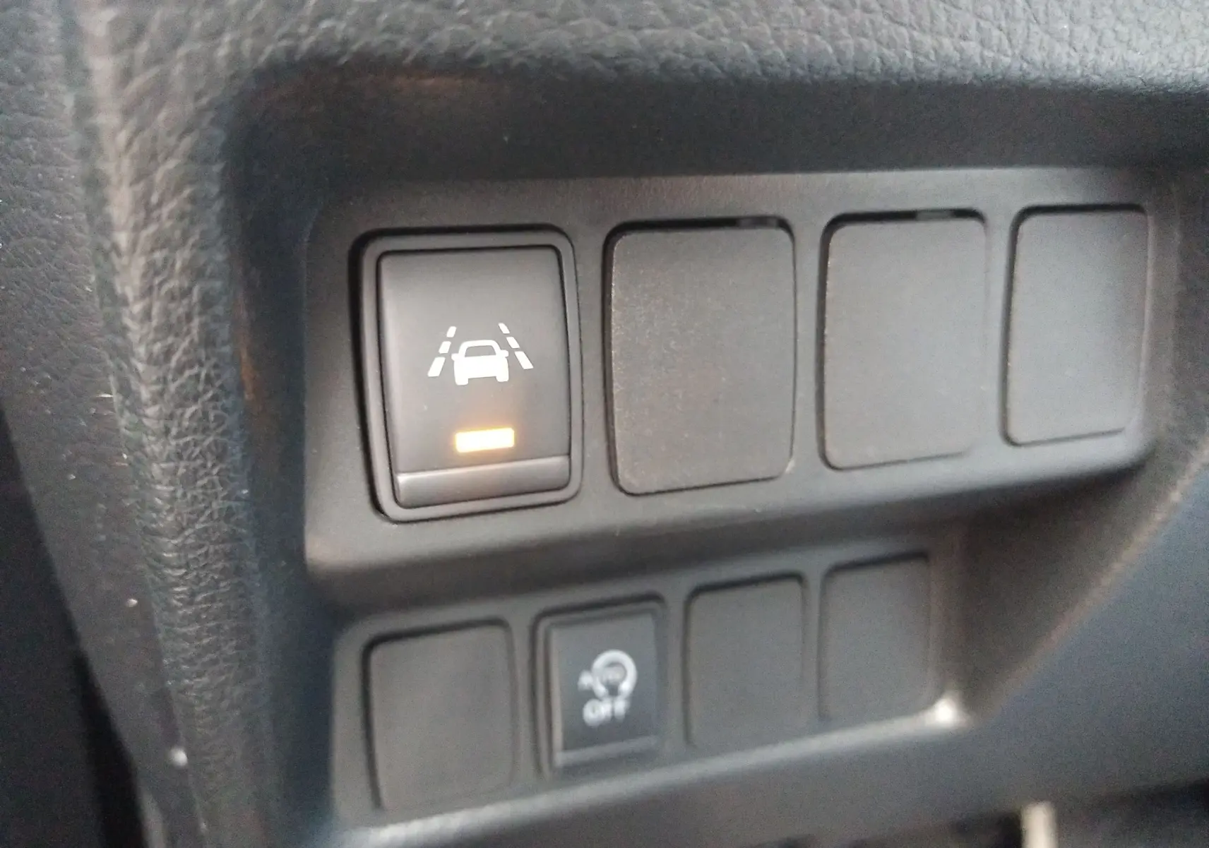 Gros plan sur les boutons de commande du tableau de bord du Nissan Qashqai noir 2019, avec témoin d'alerte de maintien de voie allumé.