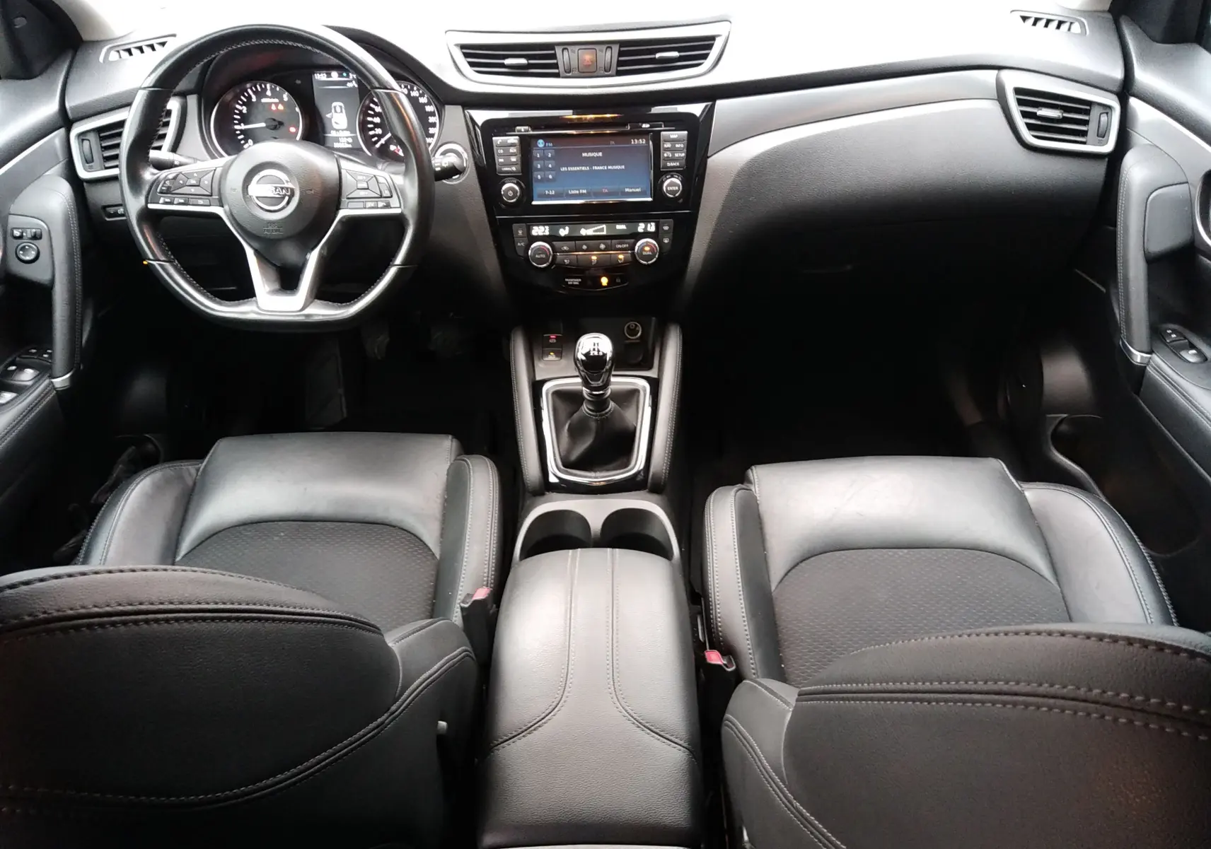 Vue intérieure avant du Nissan Qashqai 1.2 DIG-T Tekna 2019, sièges cuir noirs et tableau de bord avec écran tactile.