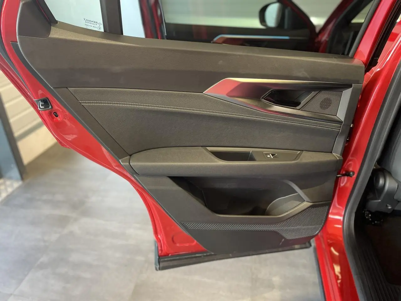 Vue intérieure de la porte arrière gauche rouge du Renault Rafale 2025 avec garniture noire et surpiqûres argentées.