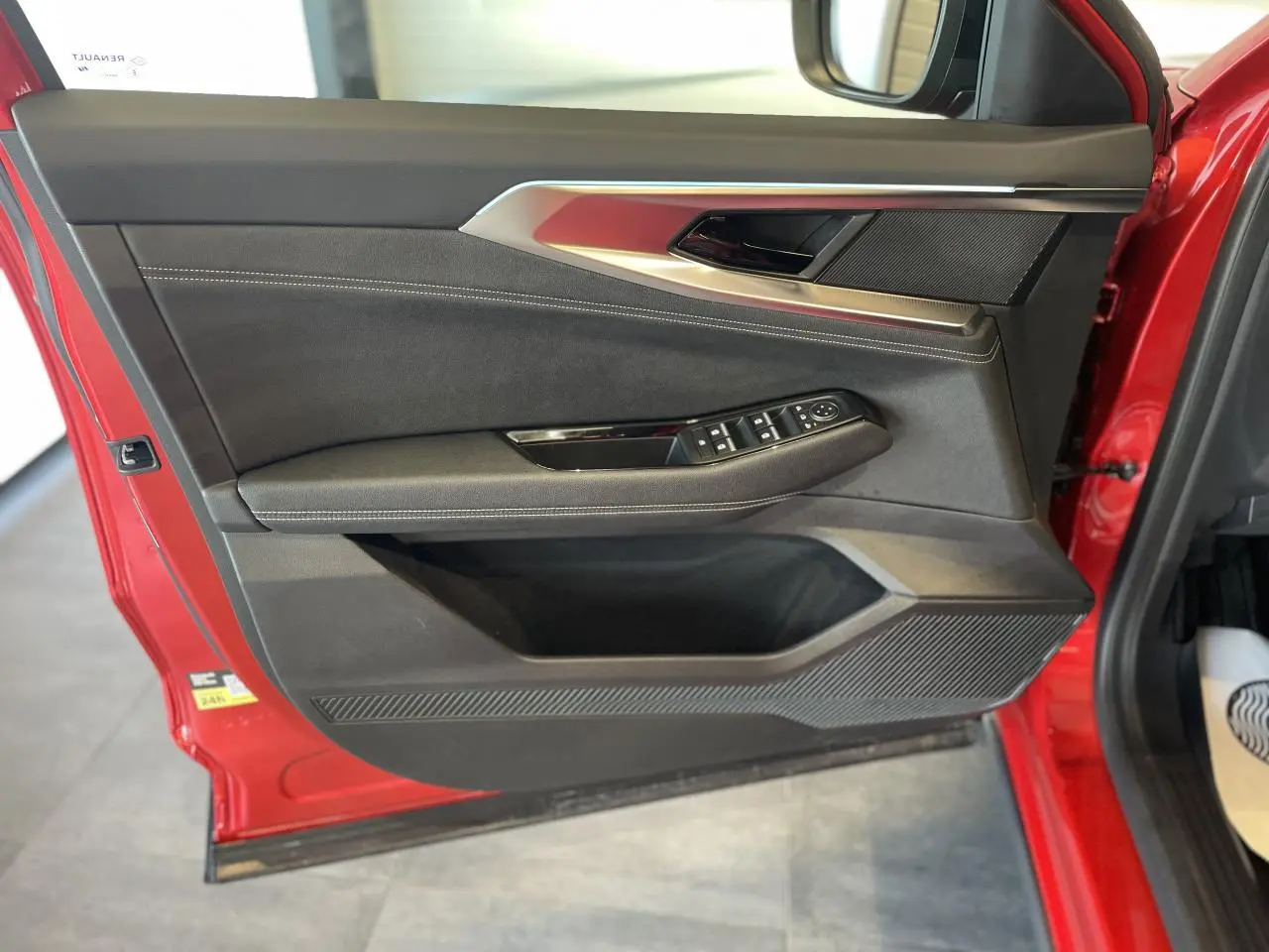 Vue intérieure côté gauche de la porte avant rouge du Renault Rafale 2025 avec commandes de vitres et inserts argentés.