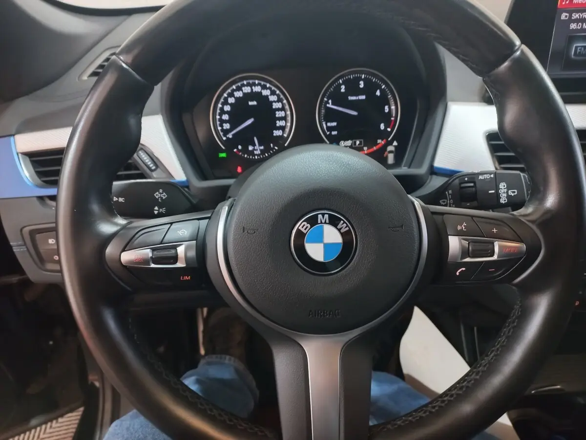 Vue rapprochée du volant cuir noir de la BMW X1 xDrive20d 2022 avec tableau de bord et commandes intégrées visibles.