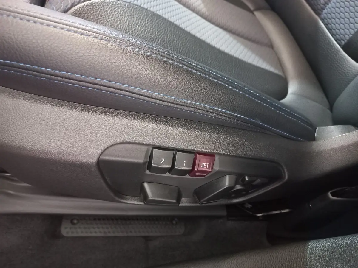 Gros plan sur les commandes de réglage mémoire des sièges en cuir noir avec surpiqûres bleues du BMW X1 xDrive20d M Sport 2022.