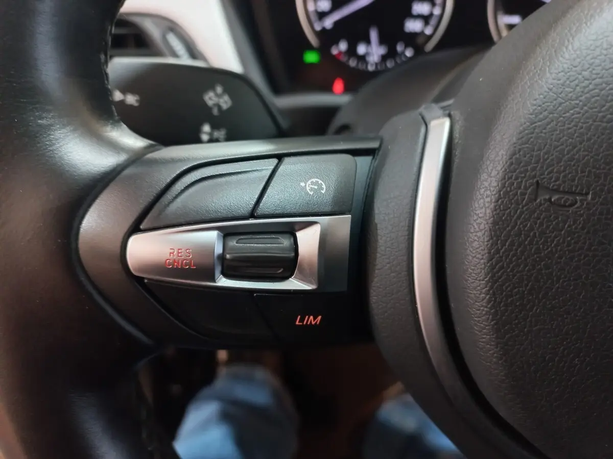 Gros plan sur les commandes du régulateur de vitesse au volant cuir noir de la BMW X1 xDrive20d M Sport 2022.