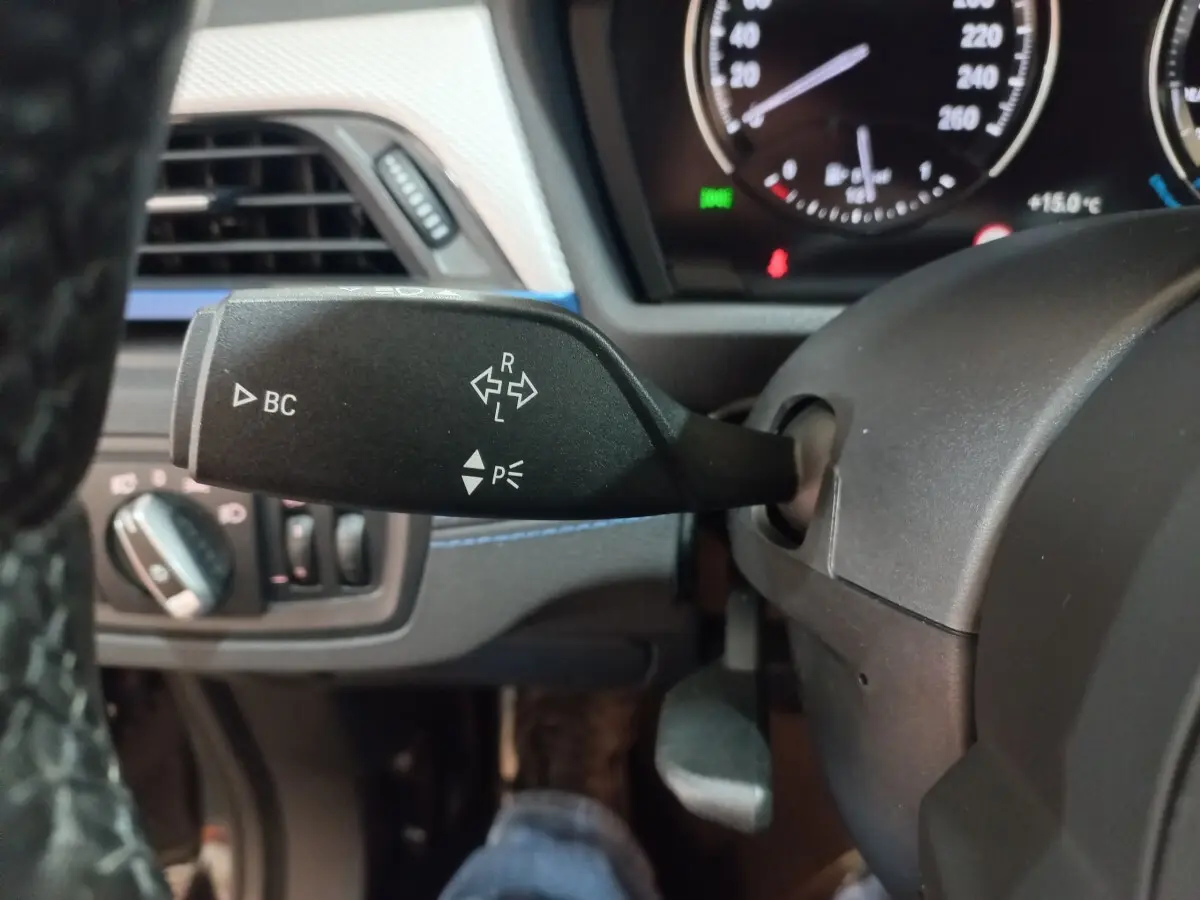 Gros plan sur la manette de clignotant à gauche du volant dans l’habitacle noir d’un BMW X1 xDrive20d 2022.