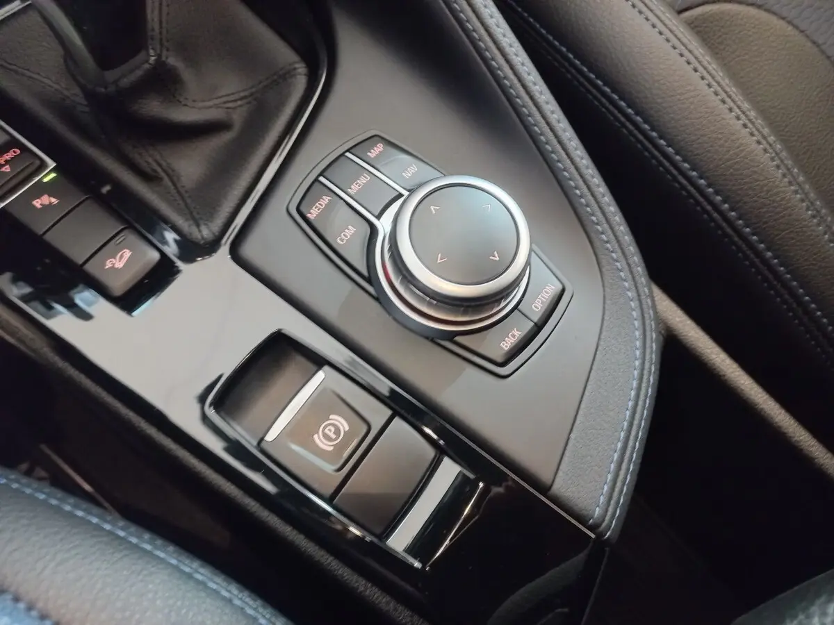 Gros plan sur la molette de commande et frein à main électrique dans l’habitacle noir de la BMW X1 xDrive20d M Sport.