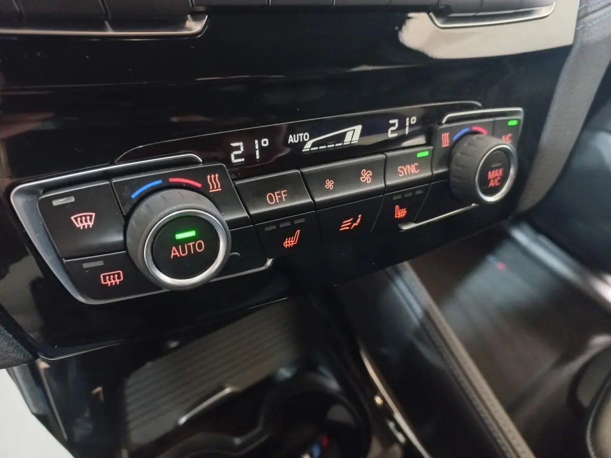 Détail de la console centrale noire du BMW X1 2022, montrant les commandes de climatisation automatique bi-zone.