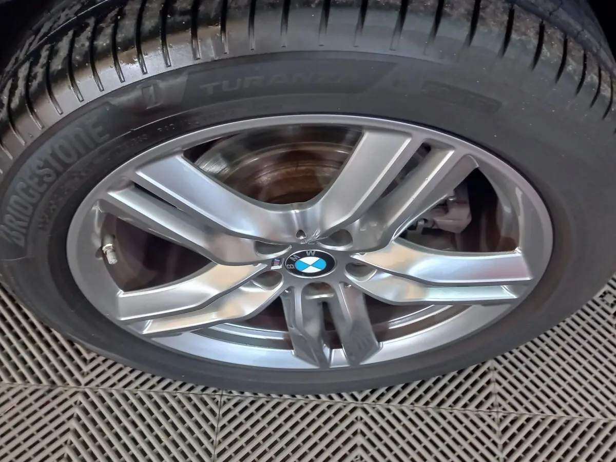 Gros plan sur la jante alliage grise et le pneu Bridgestone d’un BMW X1 xDrive20d noir, version M Sport 2022.