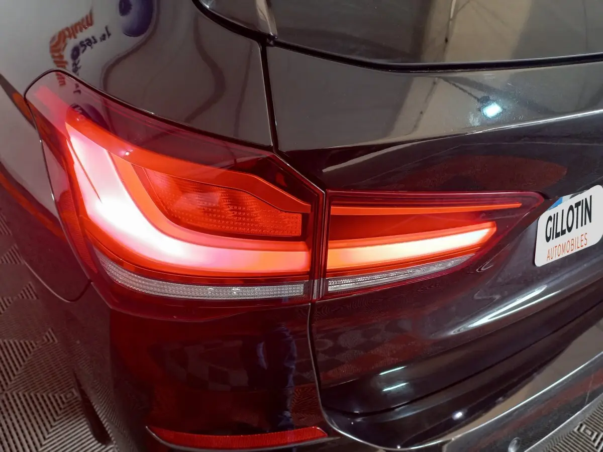 Gros plan sur le feu arrière droit allumé d’un BMW X1 xDrive20d M Sport noir, avec partie de la malle visible.