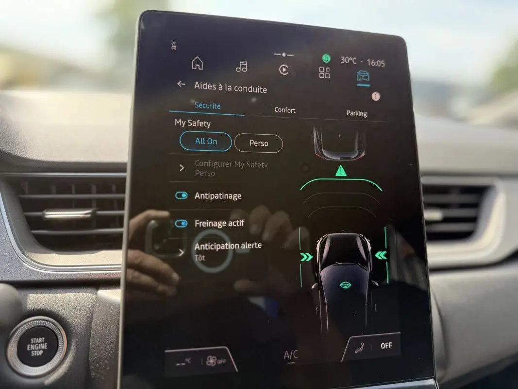 Écran tactile central du Renault Captur 2025 affichant les aides à la conduite, avec tableau de bord gris en arrière-plan.