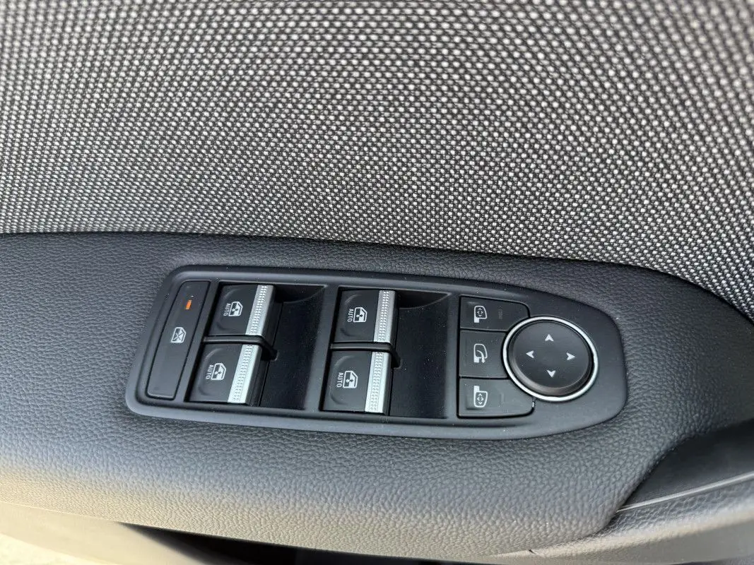 Gros plan sur les commandes de lève-vitres et rétroviseurs côté conducteur d’un Renault Captur gris Rafale 2025.