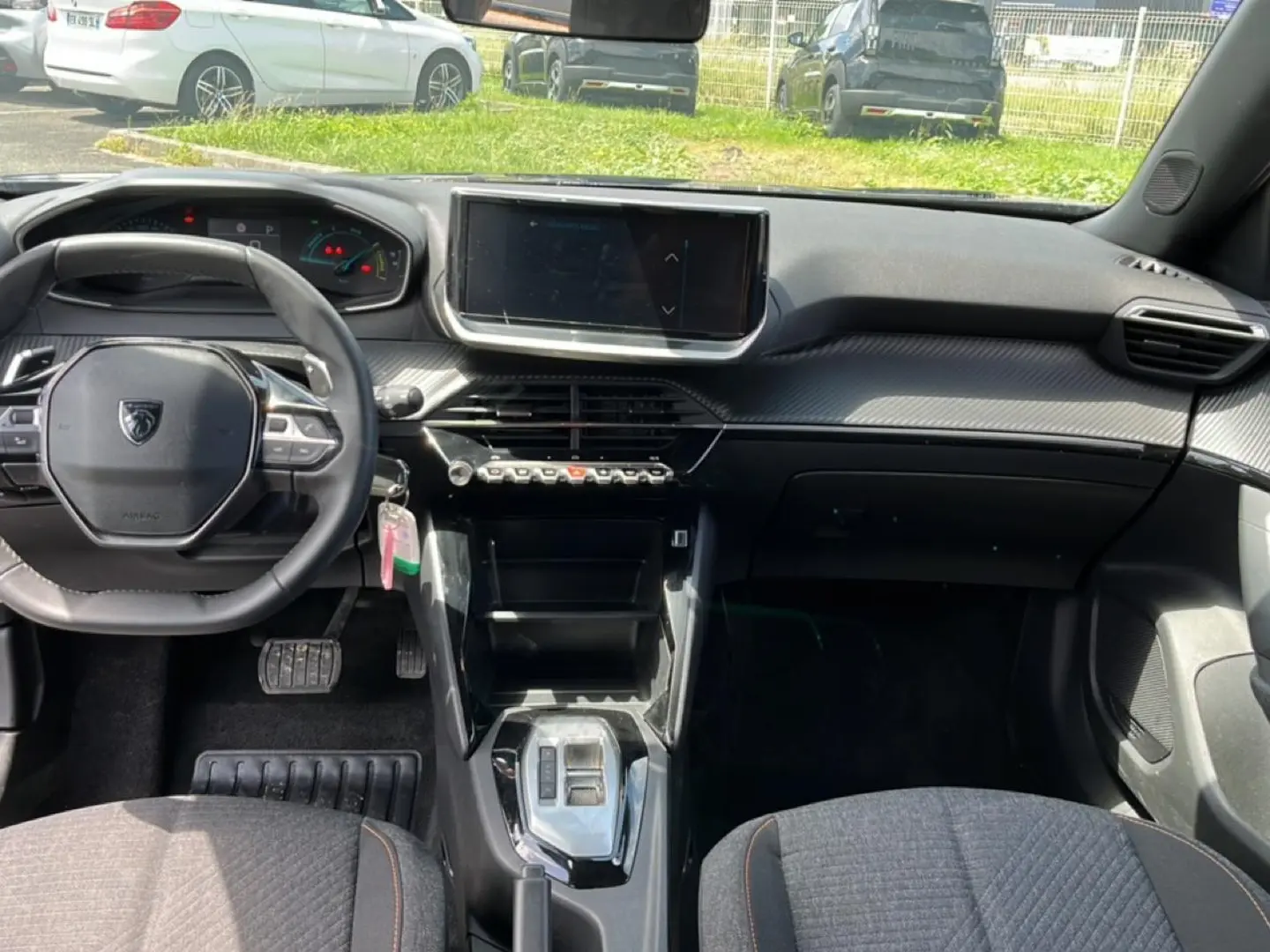 Vue intérieure frontale du tableau de bord et volant noir du Peugeot 2008 1.2 hybrid 145 style e-dcs6, avec écran tactile central.