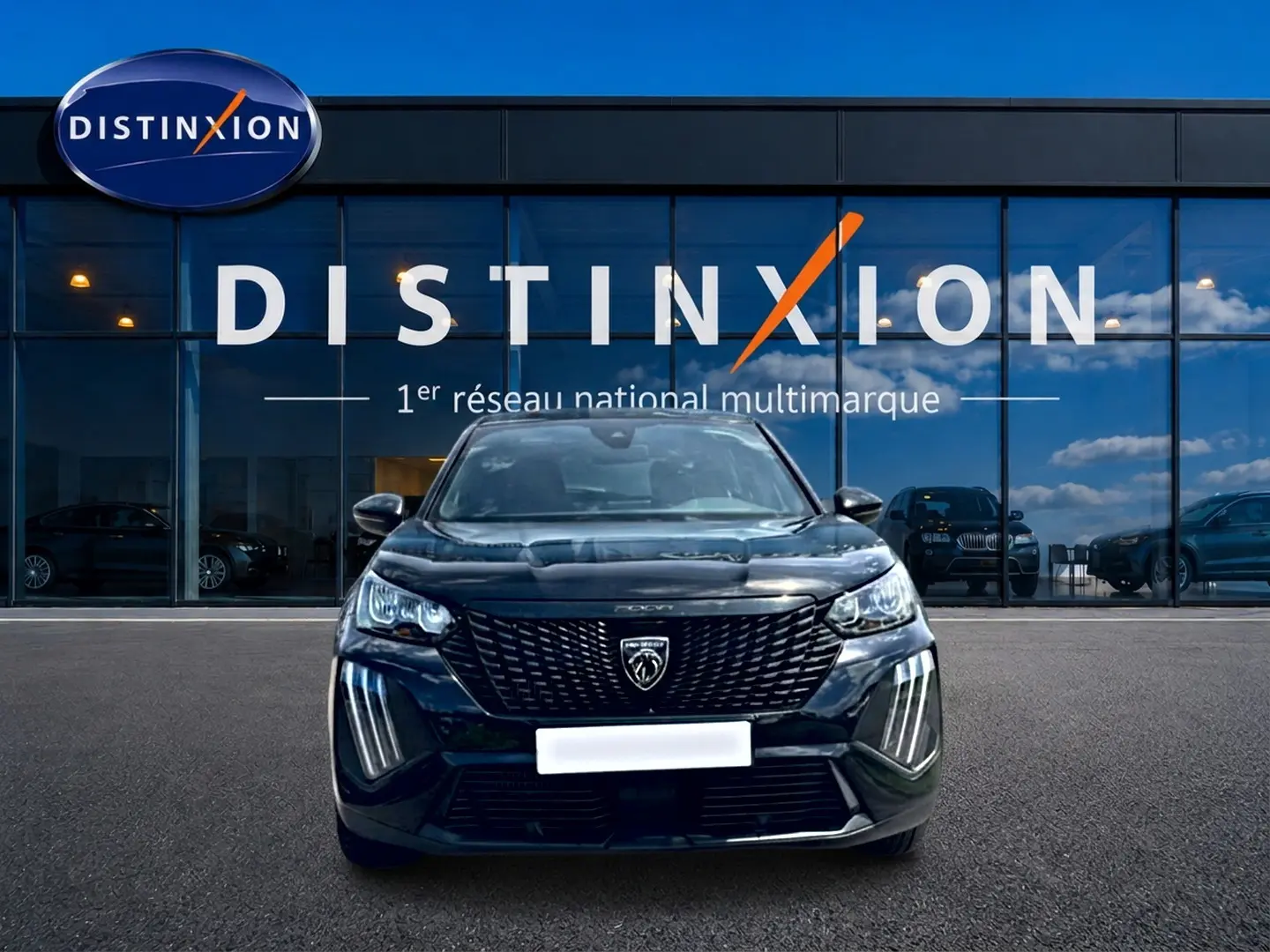 Vue frontale d'un Peugeot 2008 noir 2025 avec calandre distinctive et feux LED verticaux, devant un showroom Distinxion.