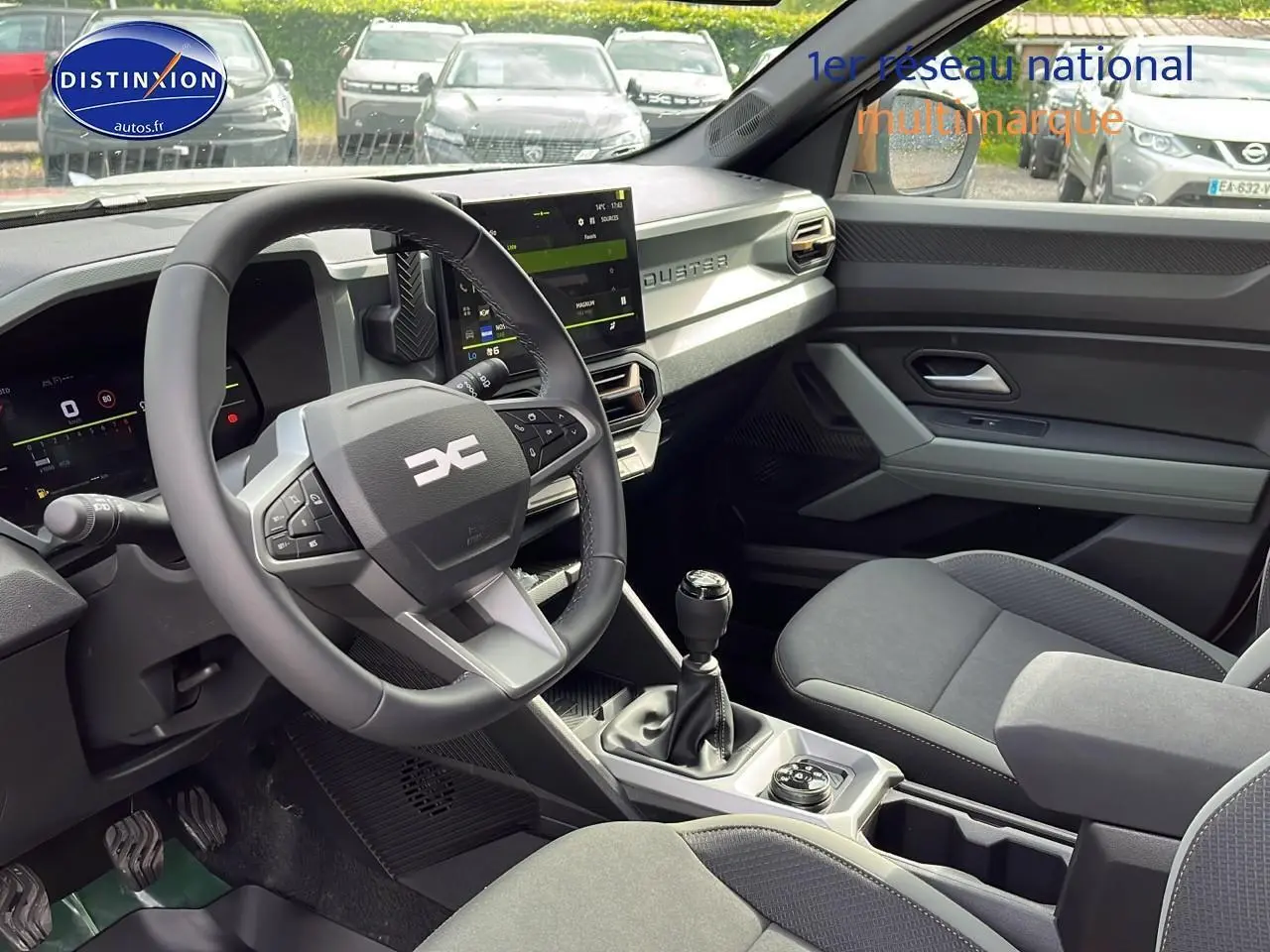 Intérieur avant du Dacia Duster 2025 avec volant multifonction, écran tactile et sellerie grise moderne.