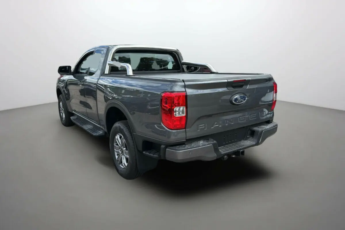 Ford Ranger gris carbone 2025 en vue 3/4 arrière droit avec rideau de benne et barres chromées.