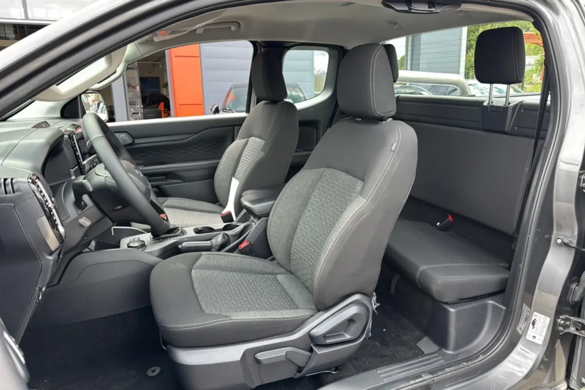 Intérieur du Ford Ranger 2025 gris carbone, vue côté gauche montrant les sièges avant et arrière Supercab avec sellerie tissu.