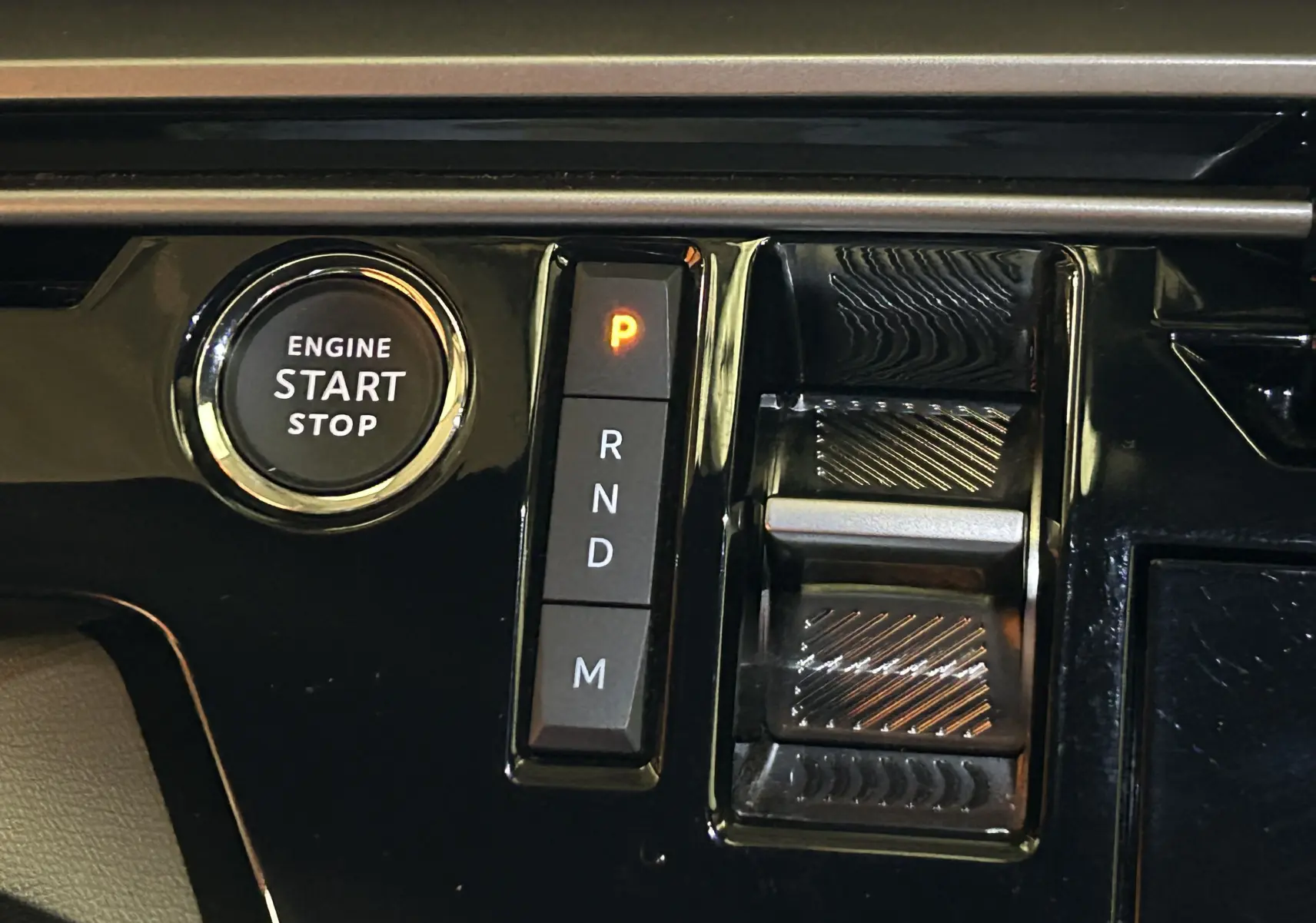 Gros plan sur la console centrale noire du Peugeot 3008 hybride 2025, avec bouton start/stop et sélecteur de vitesses électronique.