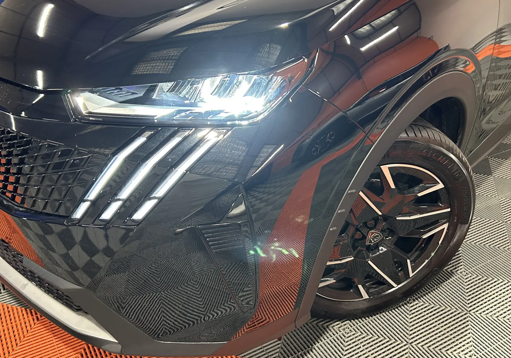 Gros plan sur l’avant droit noir du Peugeot 3008 Hybrid 2025, mettant en valeur les phares LED et la jante alliage bicolore.