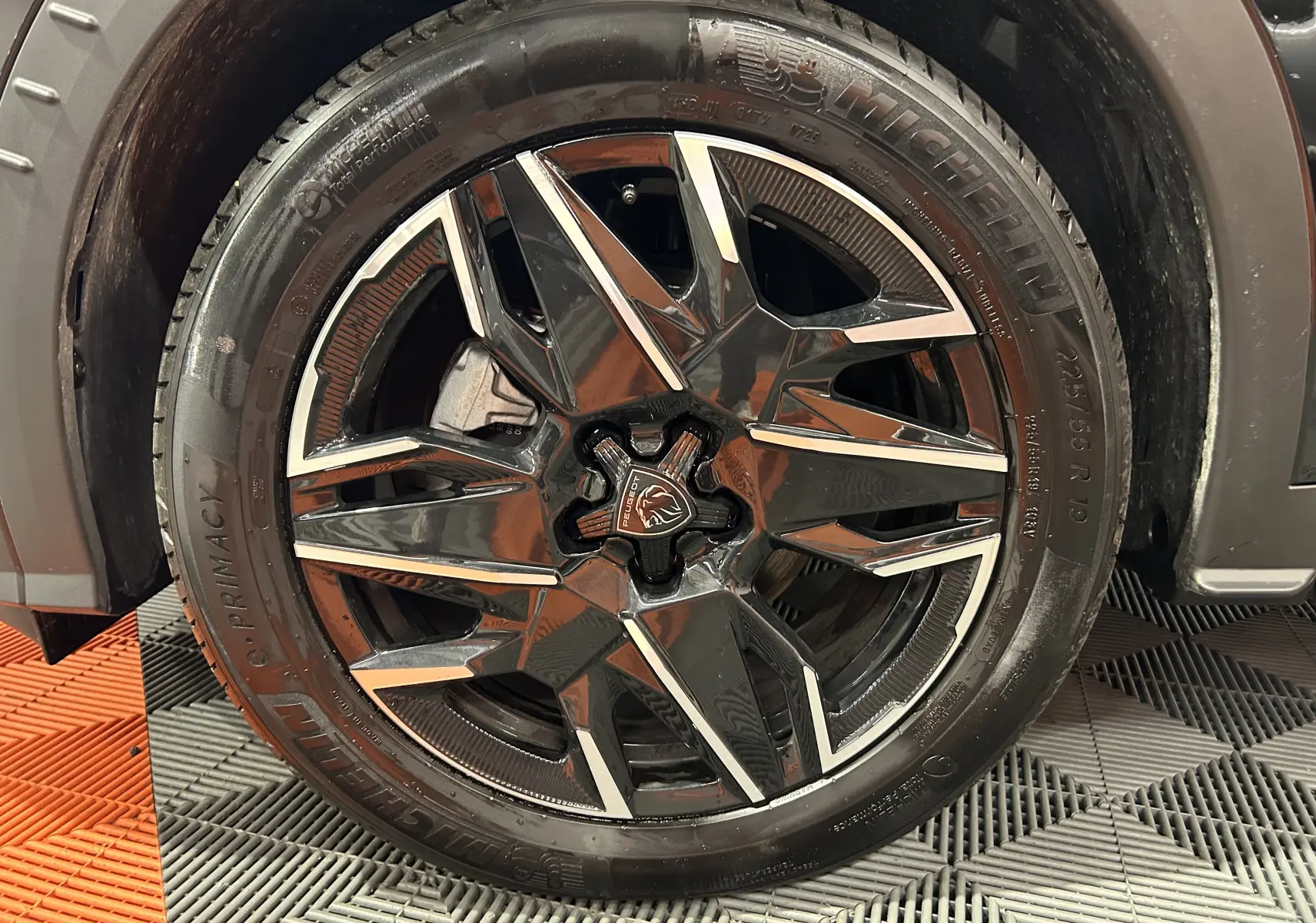 Gros plan sur la jante noire et argentée du côté avant droit du Peugeot 3008 III HYBRID 145 e-DSC6 Allure noir.