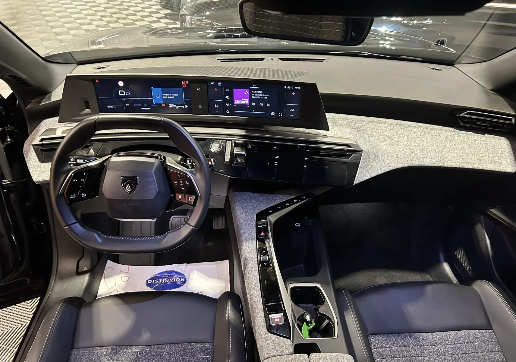 Vue intérieure avant du Peugeot 3008 noir hybride 2025, mettant en valeur le tableau de bord numérique et le volant multifonction.