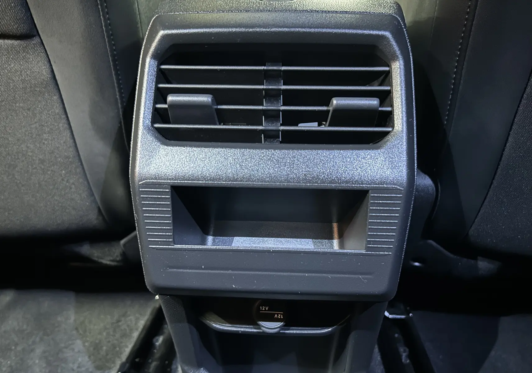 Détail de la console arrière noire du Peugeot 3008 Hybrid 2025 avec prise 12V et bouches d’aération.