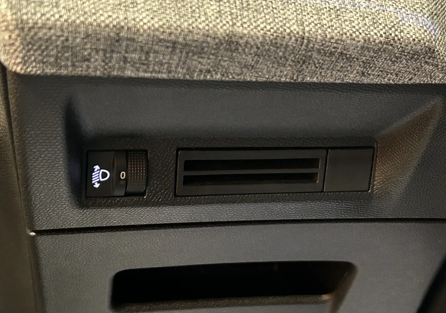 Détail intérieur du tableau de bord du Peugeot 3008 noir, montrant la molette de réglage des phares et une grille d'aération.