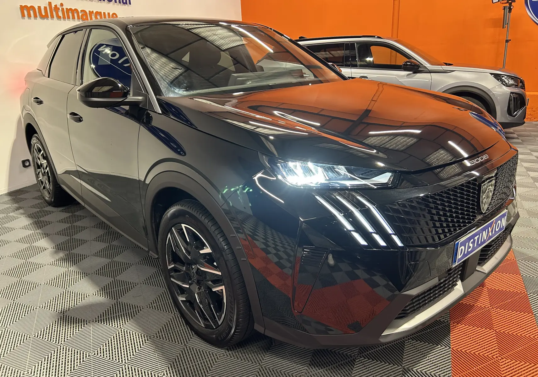 Peugeot 3008 III Hybrid noir en 3/4 avant droit, phares LED allumés et calandre distinctive au showroom.