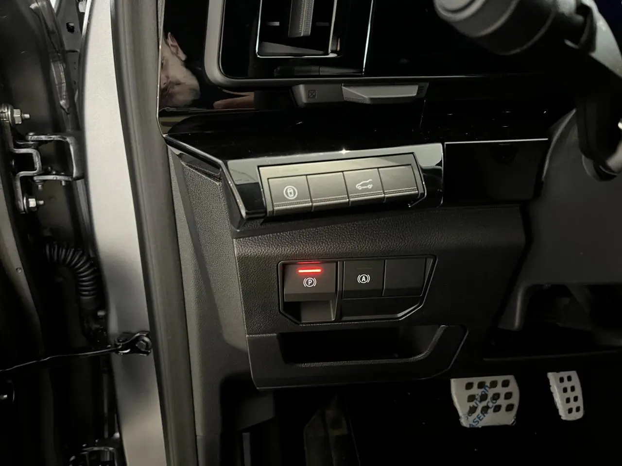 Vue intérieure côté gauche du tableau de bord du Renault Austral gris, avec commandes de frein à main et hayon motorisé.