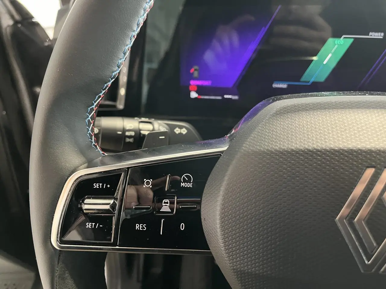 Gros plan sur le volant noir avec surpiqûres bleues du Renault Austral 2025, affichage numérique en arrière-plan.