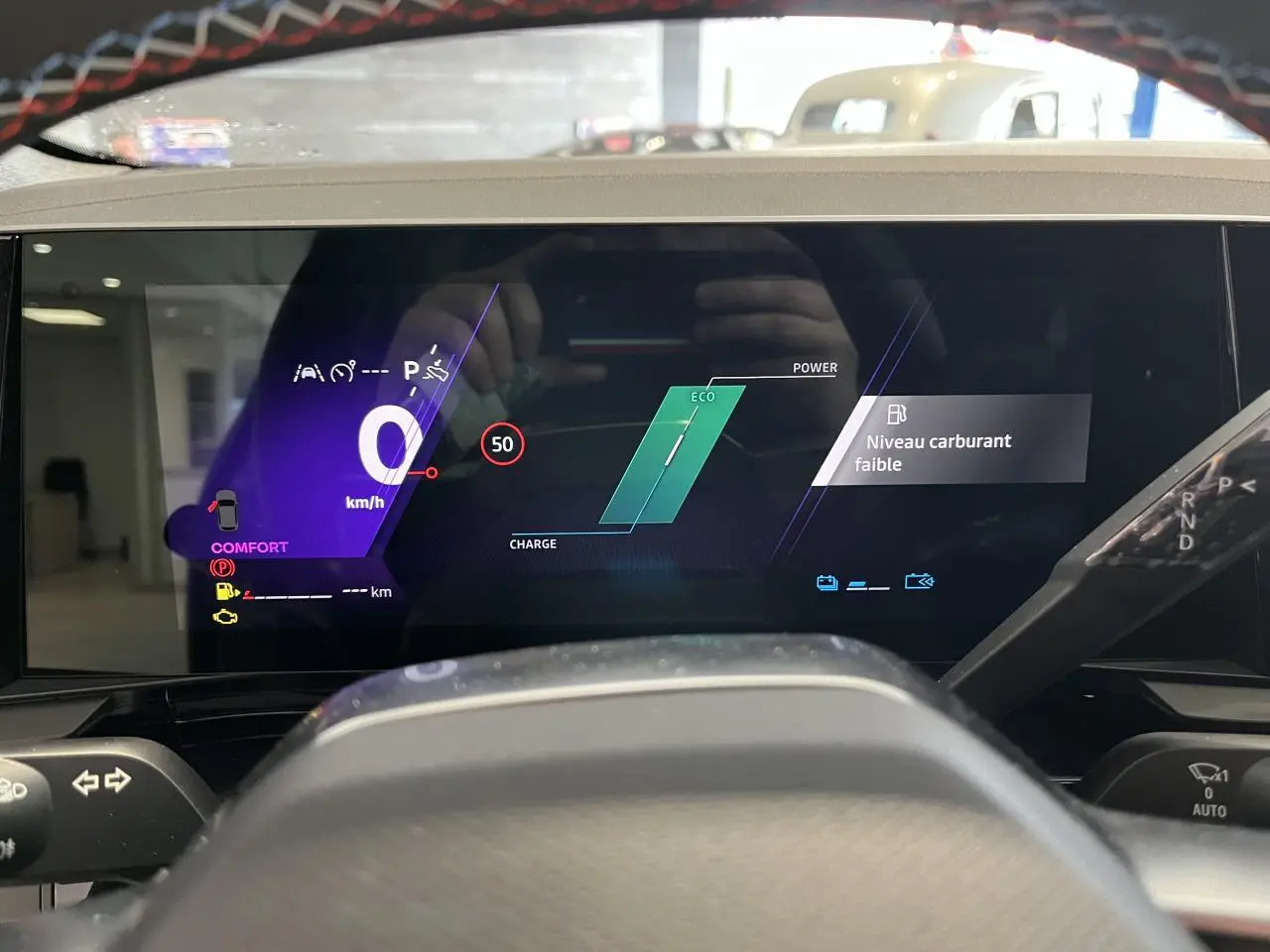 Tableau de bord numérique du Renault Austral 2025 en vue frontale, affichant vitesse zéro et alerte niveau carburant faible.