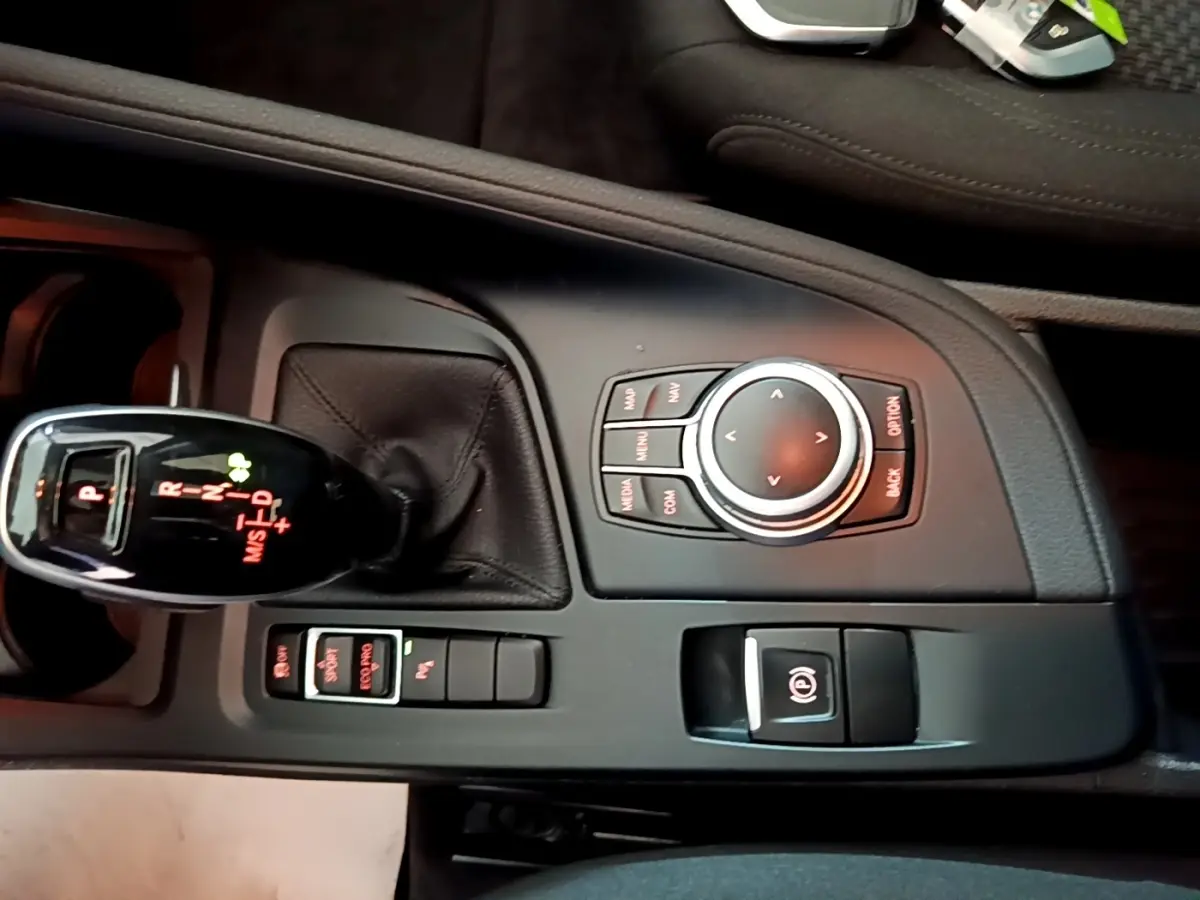 Vue rapprochée de la console centrale noire du BMW X1 2020 avec levier de vitesses automatique et molette de commande.