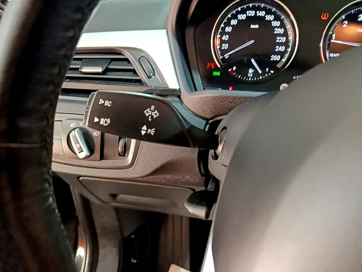 Gros plan sur le tableau de bord noir et le volant cuir d'une BMW X1 2020, avec compteur et commandes visibles.