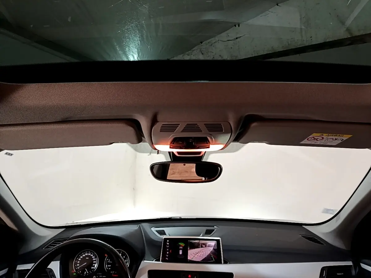 Vue intérieure du tableau de bord et volant noir d'une BMW X1 2020 avec écran tactile central allumé.