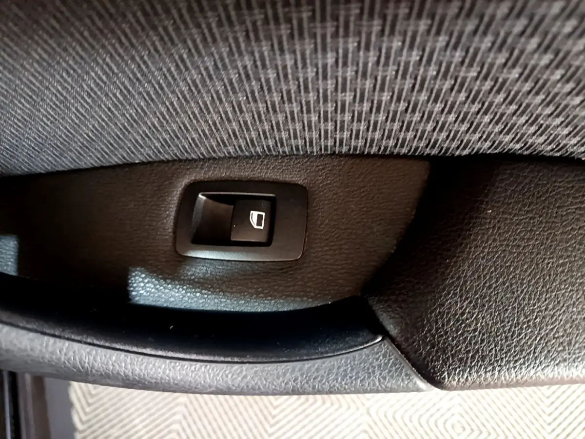 Bouton de commande de lève-vitre arrière sur panneau de porte intérieur noir d'une BMW X1 sDrive20i 2020.