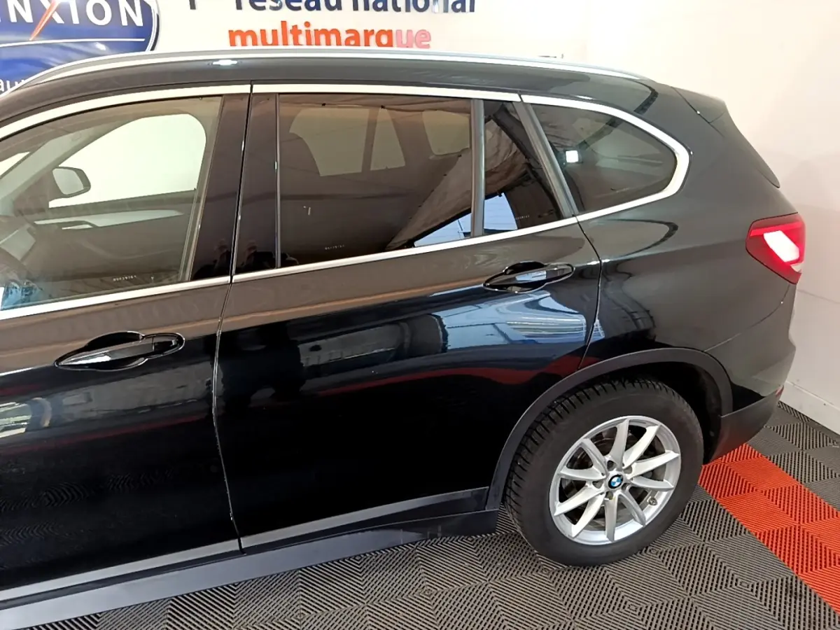 Vue latérale côté droit d'un BMW X1 noir 2020 avec jantes alliage et feux arrière allumés.