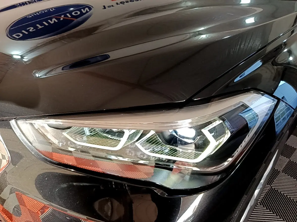 Gros plan sur le phare avant droit LED d’un BMW X1 noir, mettant en valeur les lignes modernes et précises du véhicule.